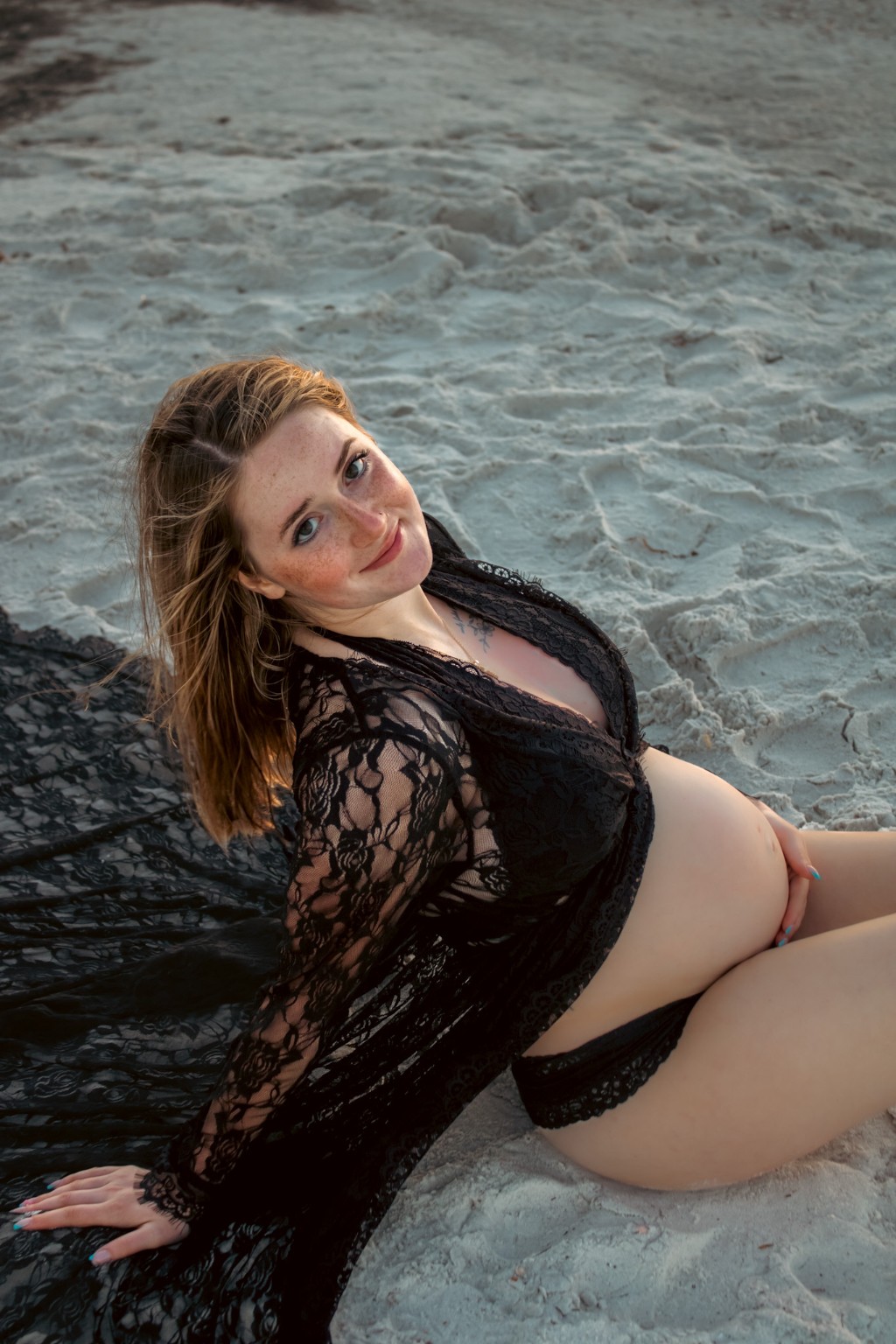 An expectant mother reclining in the shallow surf