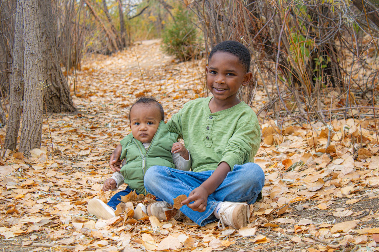 Two children sitting among autumn leaves