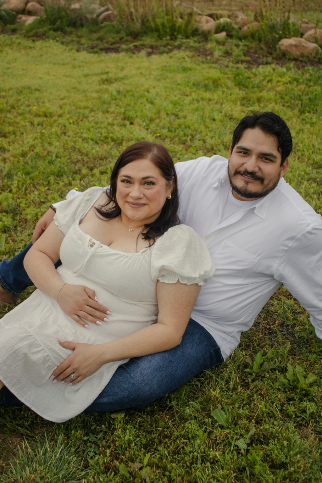 Expectant parents seated together in the grass