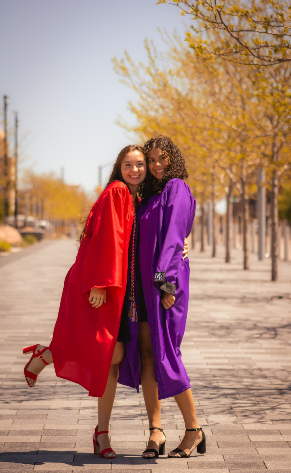 Two graduates celebrating in red and purple gowns
