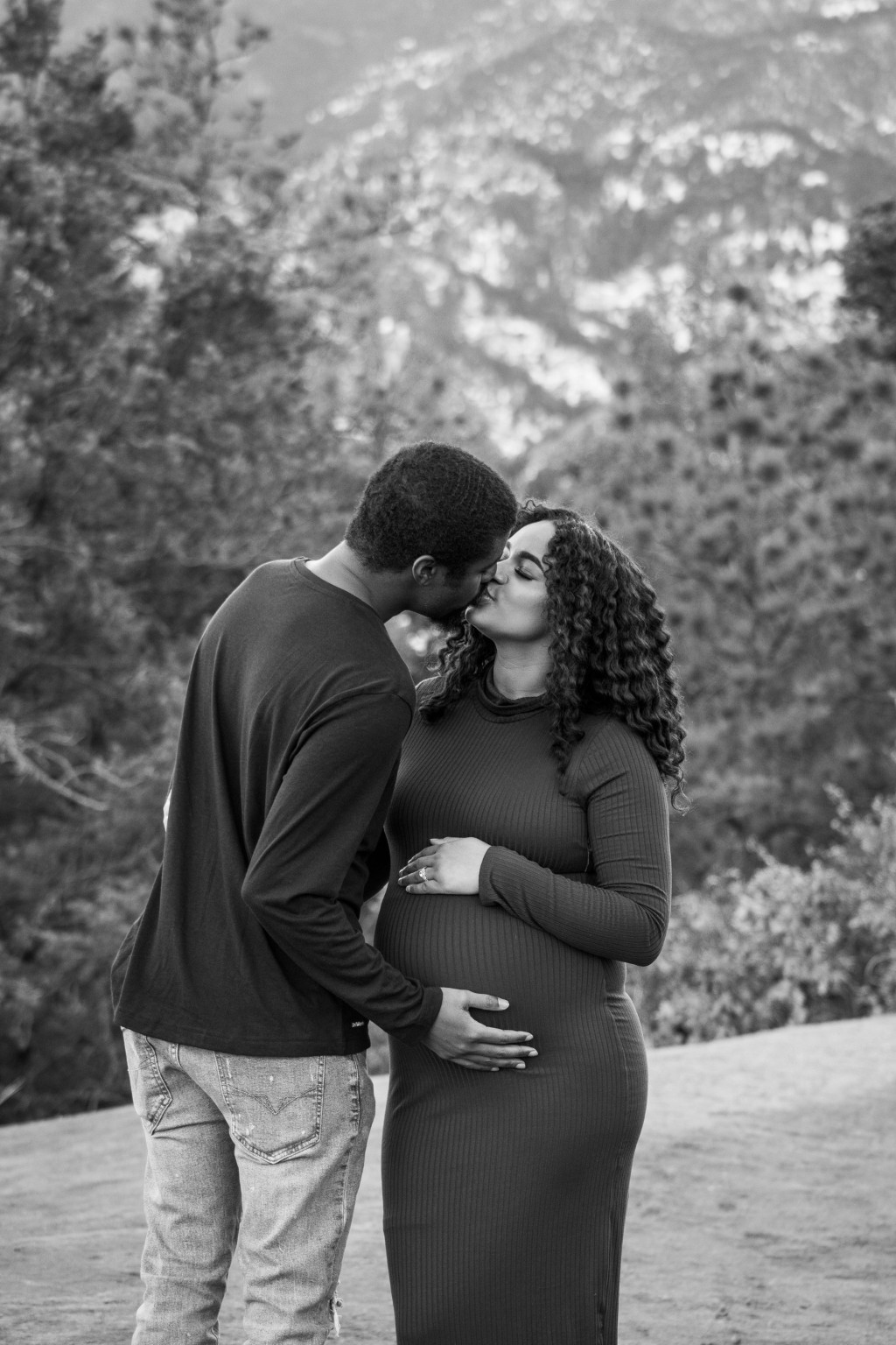 Expectant parents sharing a kiss in black and white