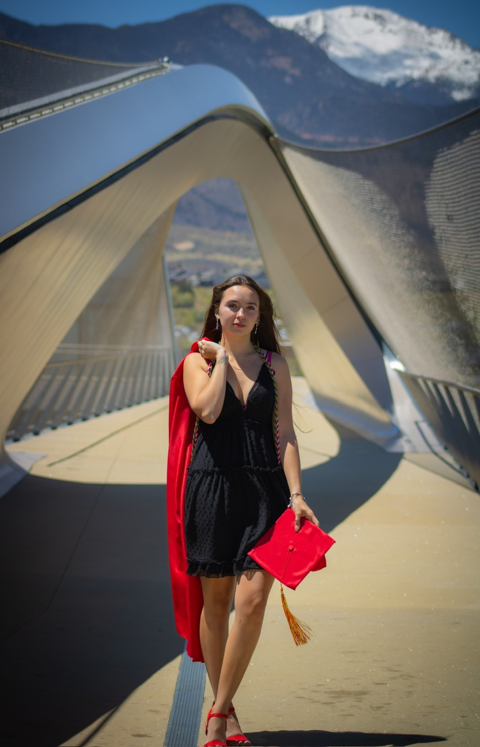 A graduate with a red cap on a sculptural bridge