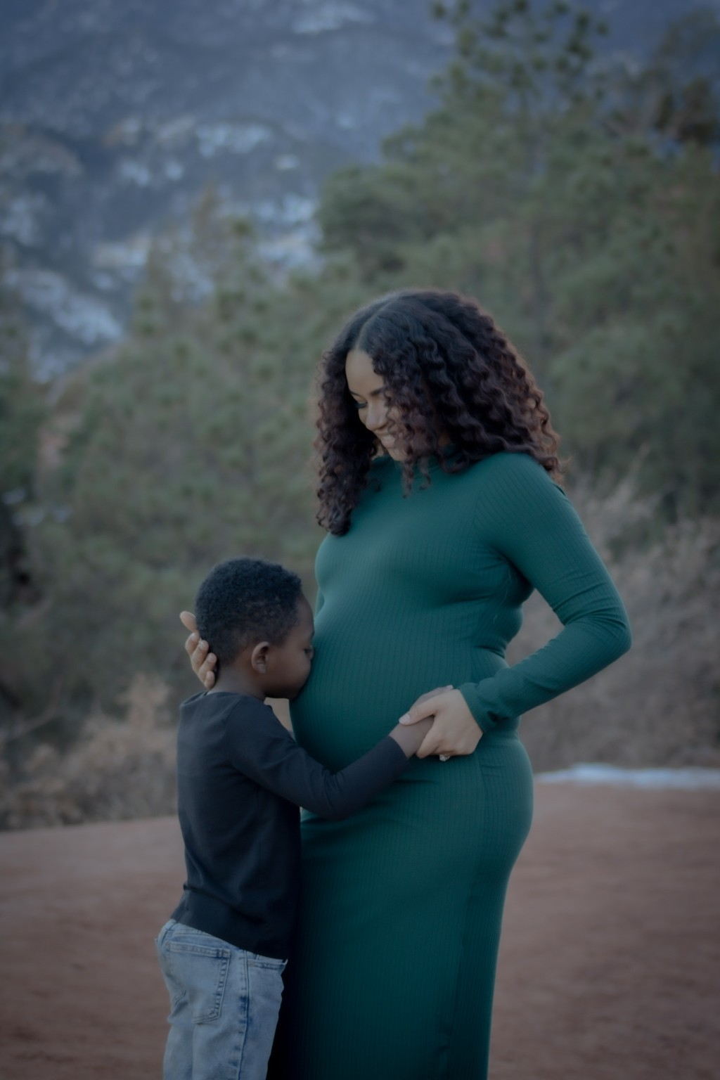 An expectant mother and child together beside the red rocks