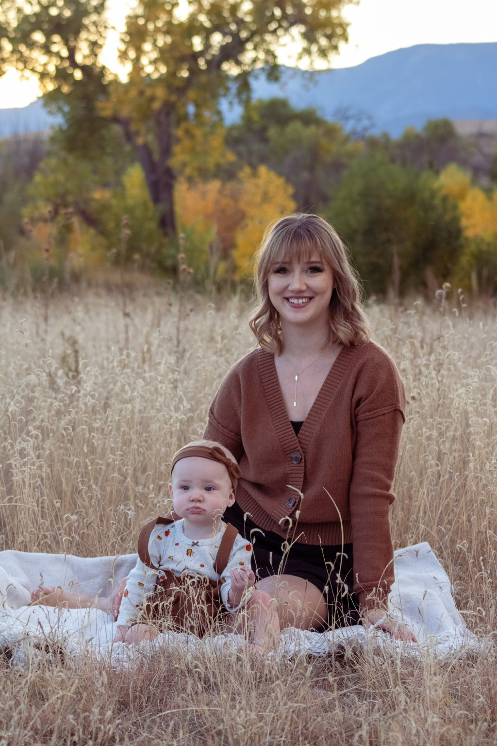 A mother and baby seated in an autumn meadow