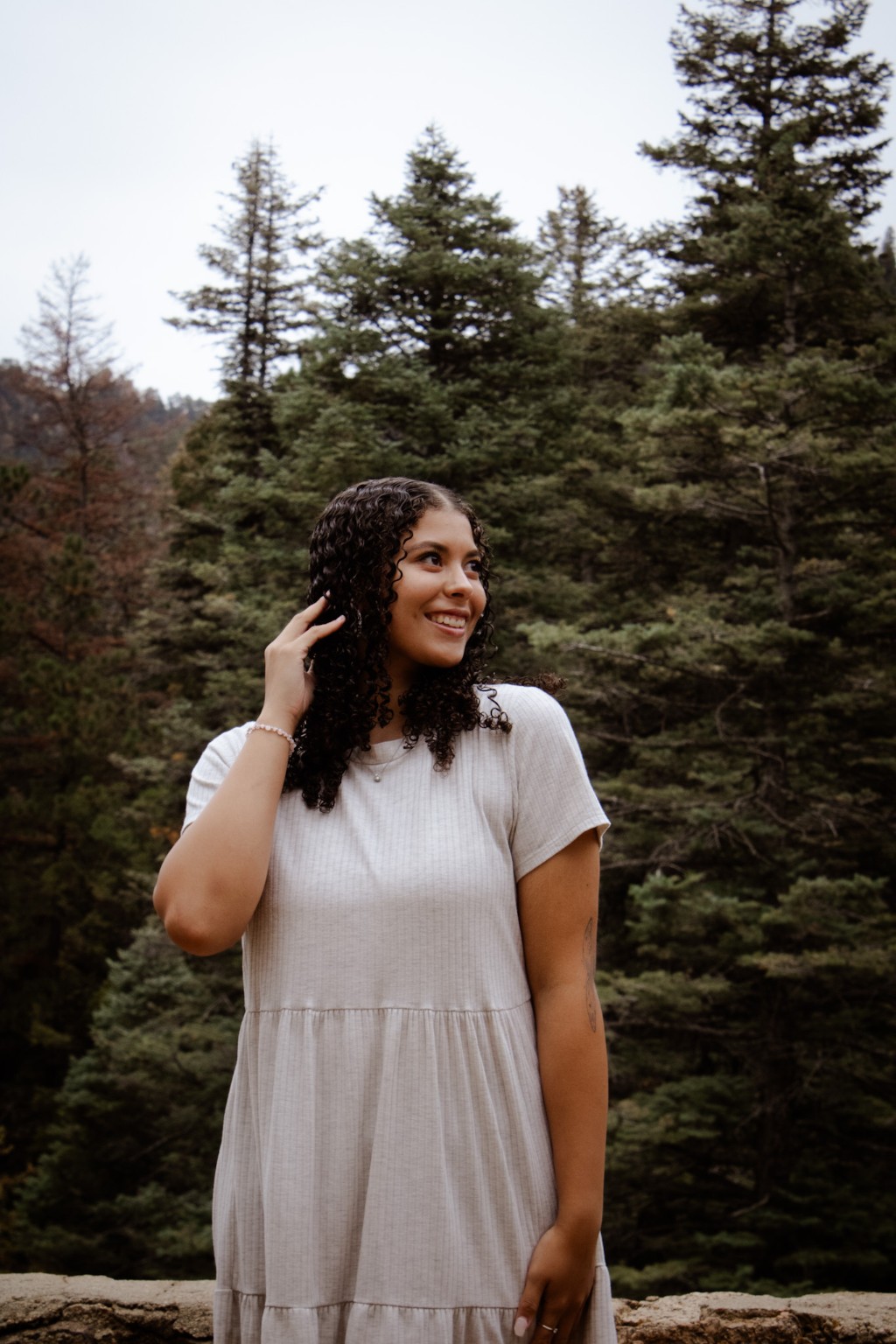 A portrait in a white dress beside the evergreens